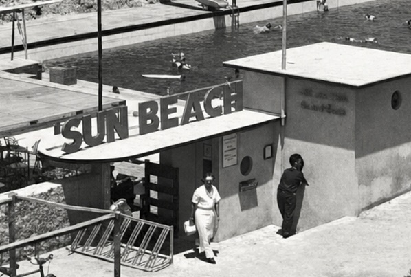 The club's entrance in the 1960s: a white pavilion topped with a sign in big letters, in front of pools busy with swimmers